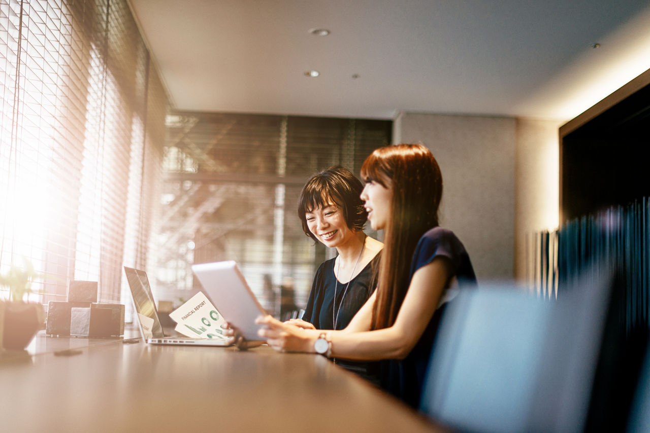 Two young Japanese businesswomen discuss options for investment and other development projects in modern office. Image taken with Nikon D800 and developed from RAW in XXXL size. Location: Kyoto, Japan