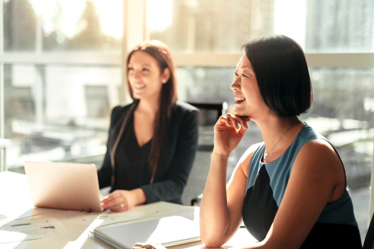 Korean businesswoman listening to discussion at meeting with colleague in modern business office