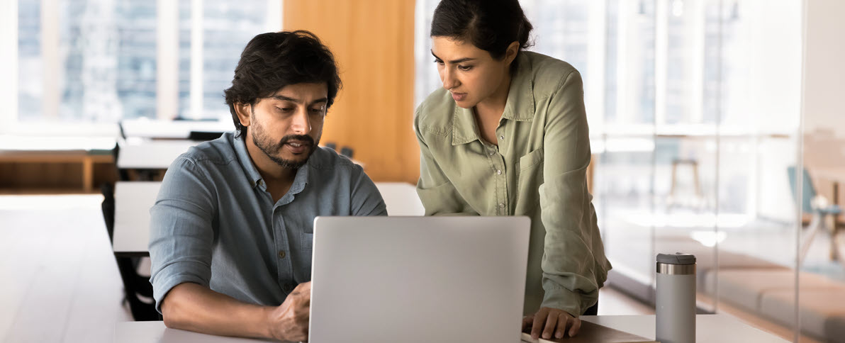 Two employees looking at a laptop 