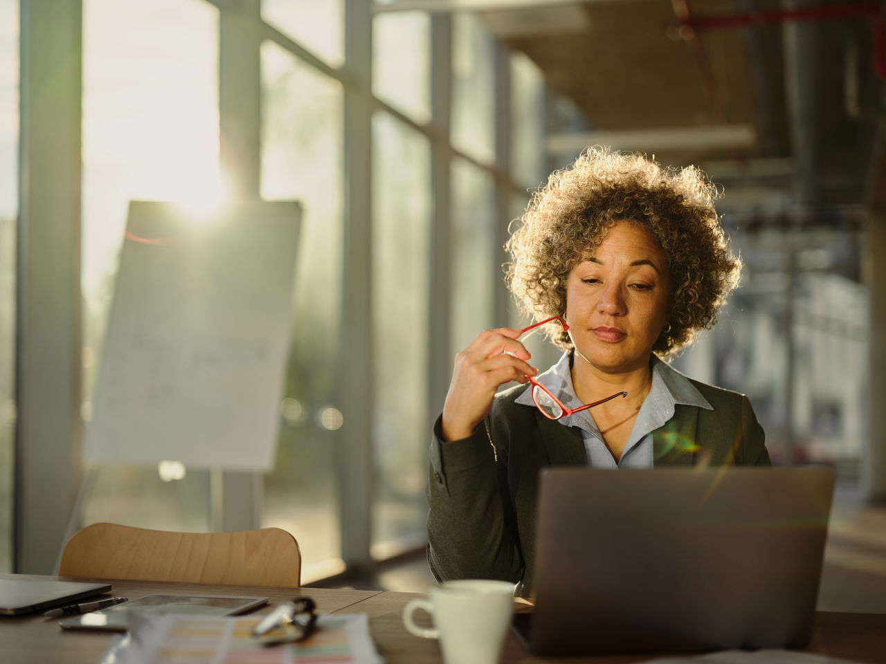 Mature female entrepreneur brainstorming while reading on a computer in the office.