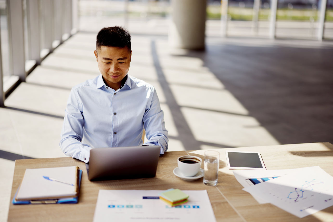 Young Chinese entrepreneur surfing the Internet on a computer in the office. Copy space.