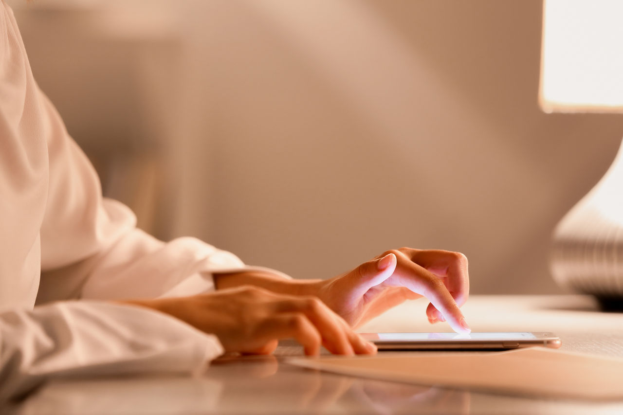 Woman using mobile phone at table in evening, closeup