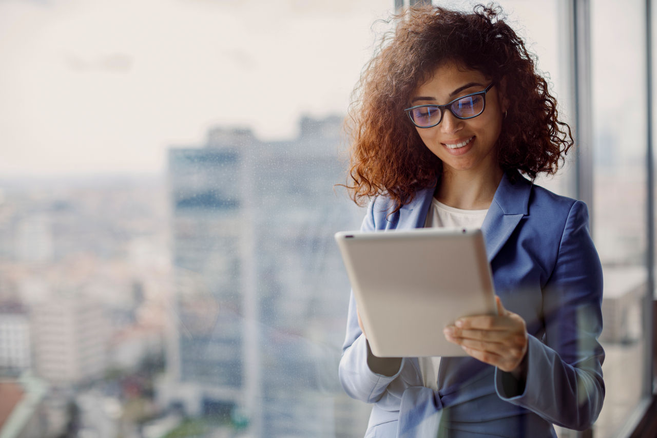 Young smiling businesswoman using digital tablet in office