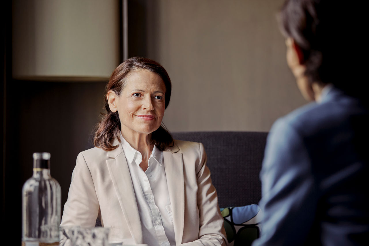 Smiling mature businesswoman looking at female colleague discussing. Businesswomen are working together. They are planning strategy.
