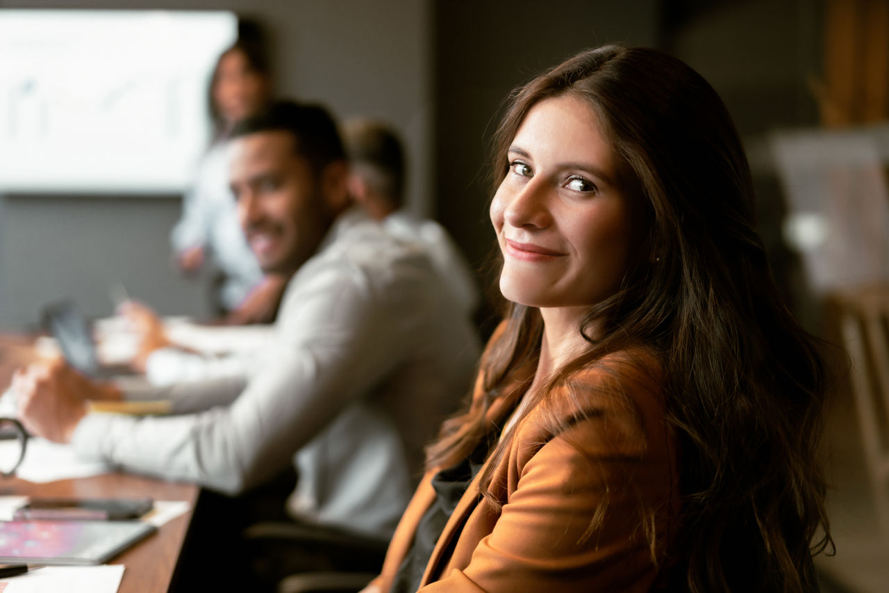 Portrait of a happy Latin American business woman in a meeting at the office and looking at the camera smiling. This photo was taken in Colombia