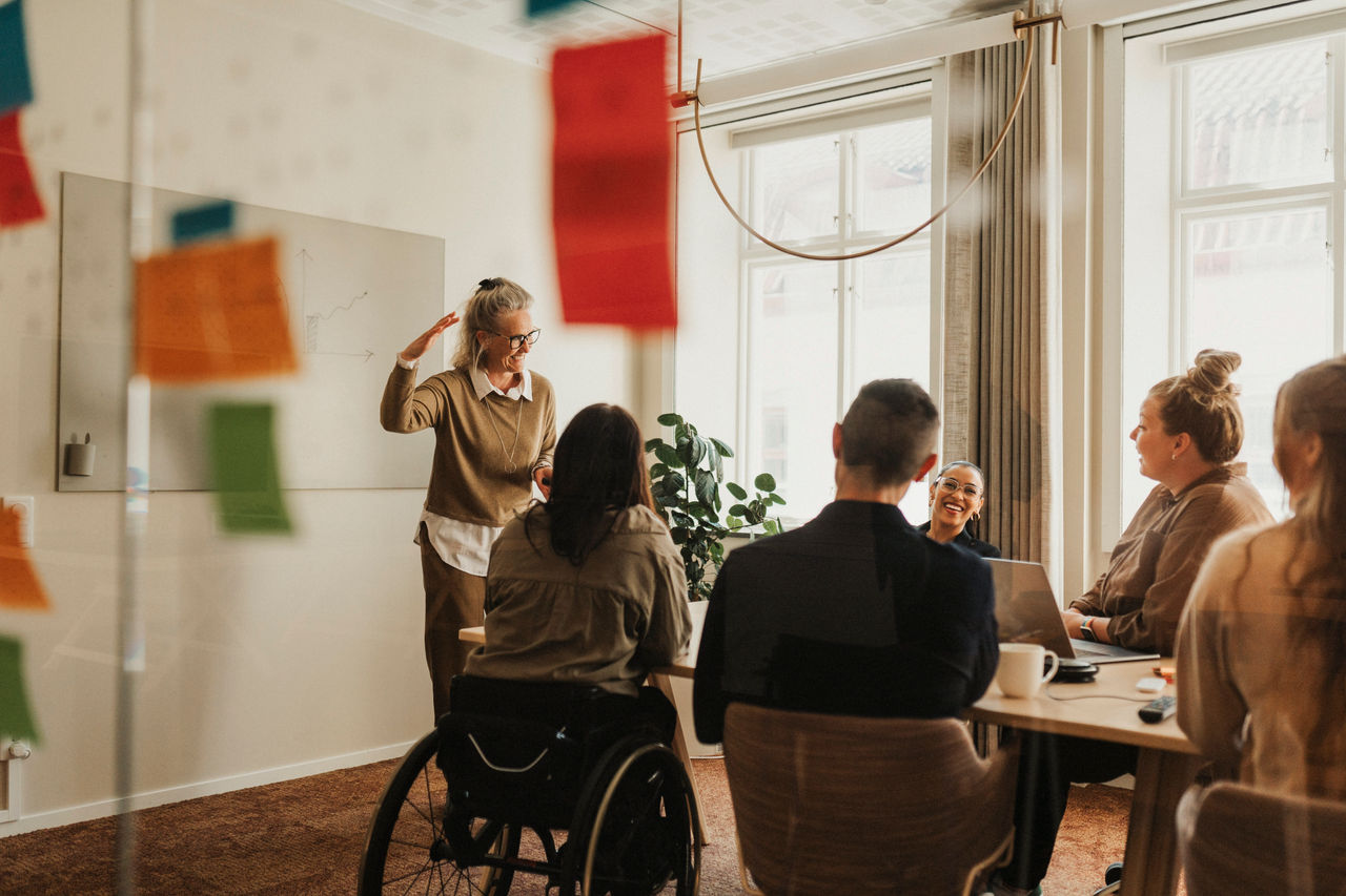  Happy female business professional explaining ideas to colleagues in meeting room